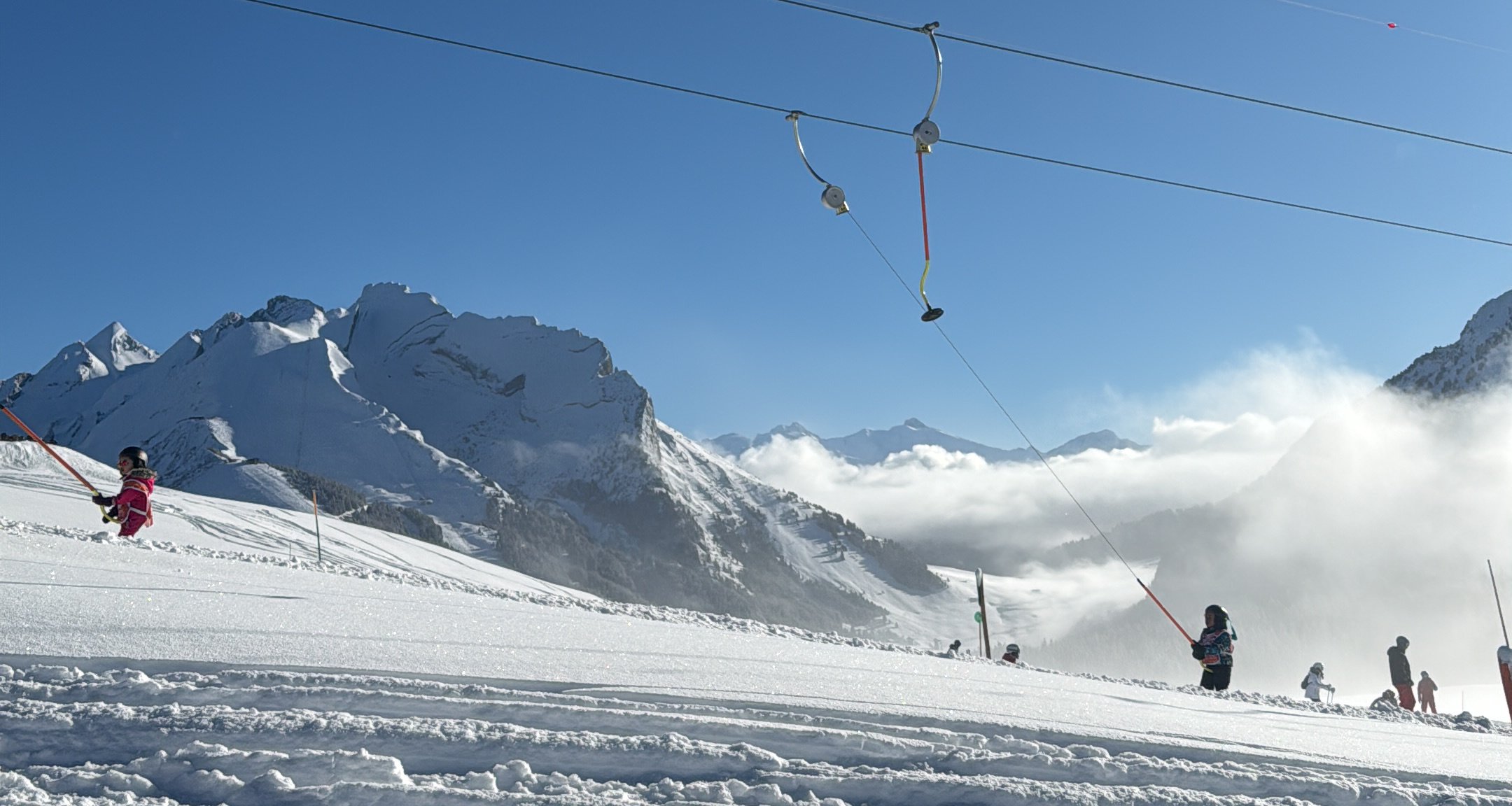 Téléski sur les pistes, sommets enneigés et mer de nuages