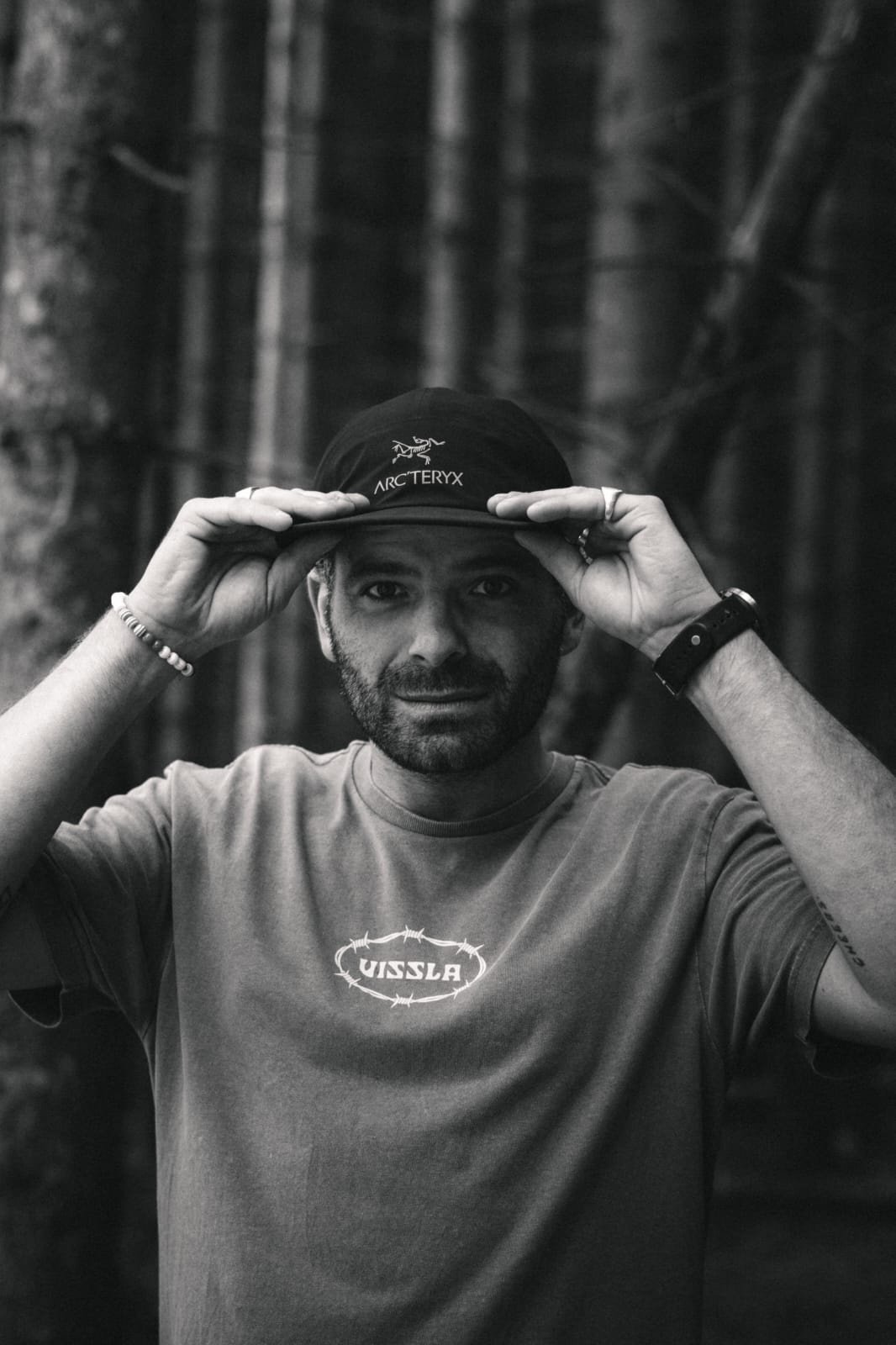 Portrait en noir et blanc de Mathieu Vittoz Duval, les mains sur sa casquette
